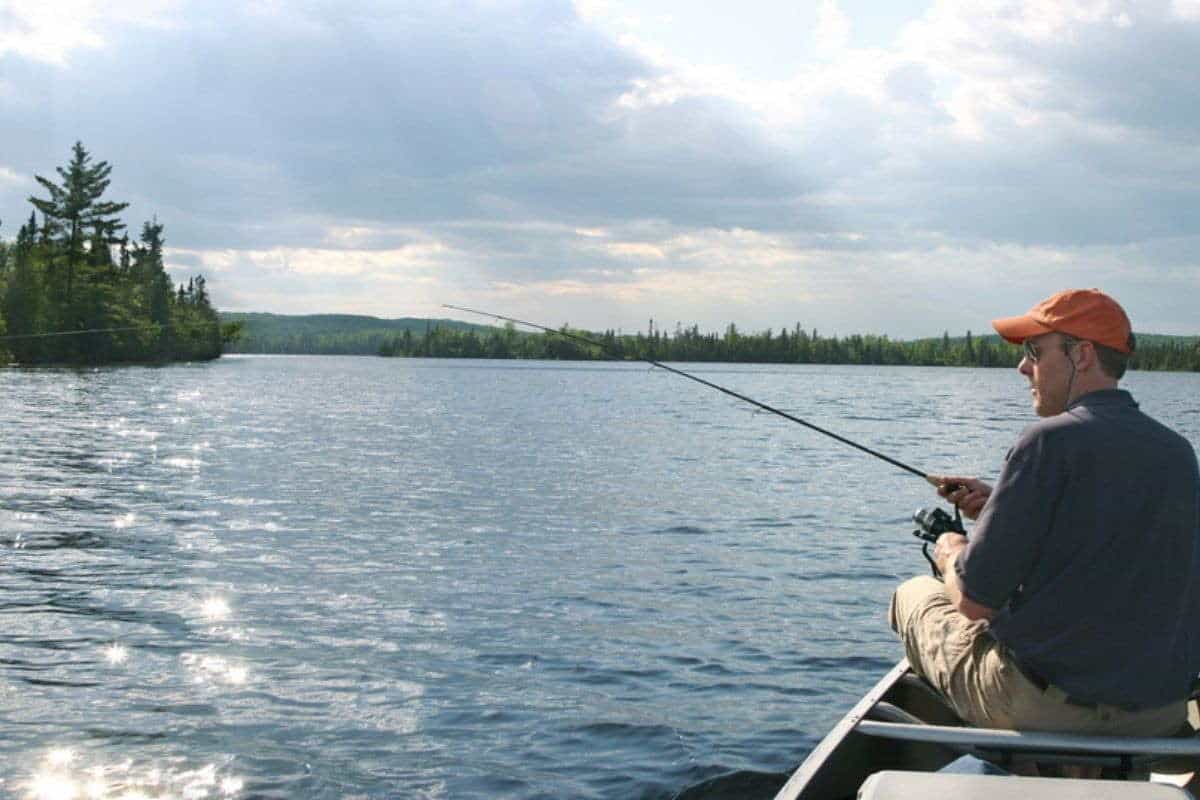 man fishing on top of canoe