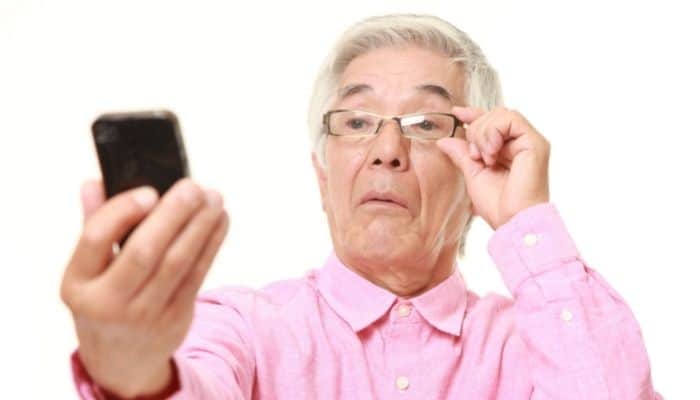 man in glasses holding smartphone at arm's length