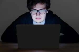 man with glasses in front of laptop