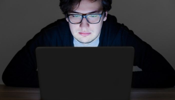 man wearing computer glasses in front of laptop