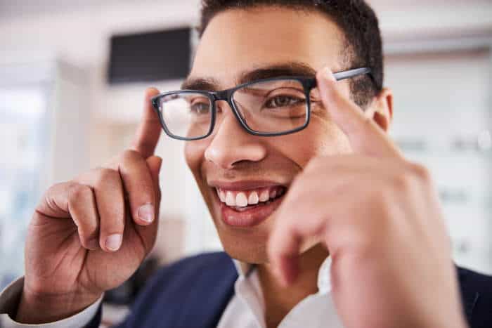 man putting glasses on with index fingers on temples