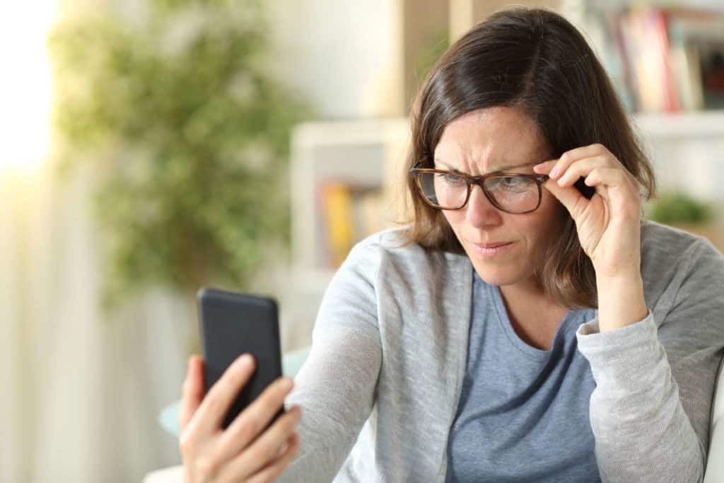 woman in glasses squinting at phone