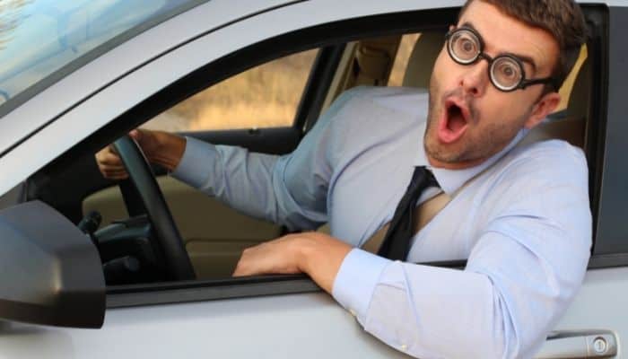 driver wearing glasses leaning out of window with shocked expression