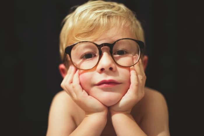 little kid wearing glasses holding face
