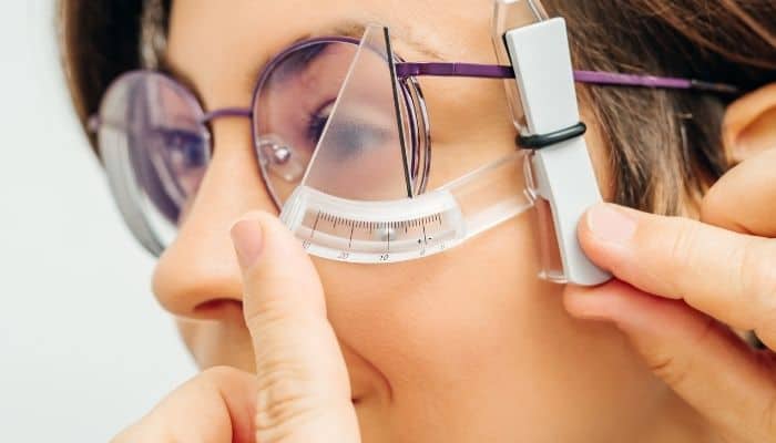 optometrist measuring eyeglass frame tilt on woman