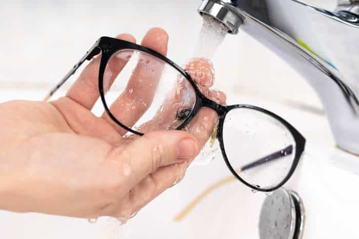 rinsing eyeglasses under faucet