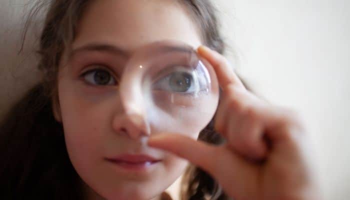 girl with magnified eye through convex lens