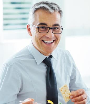 man in rectangle glasses holding a cracker