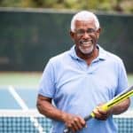older gentleman wearing glasses holding tennis racket