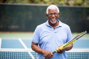 older gentleman wearing glasses holding tennis racket