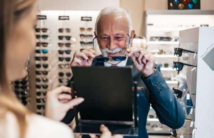 man trying on glasses in retail optical shop
