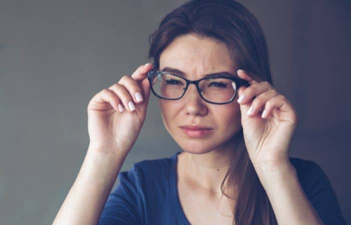 woman squinting eyes through glasses