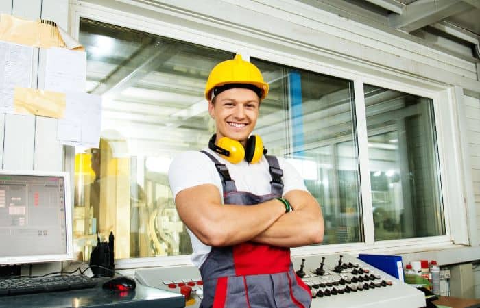smiling young worker wearing safety helmet with crossed arms