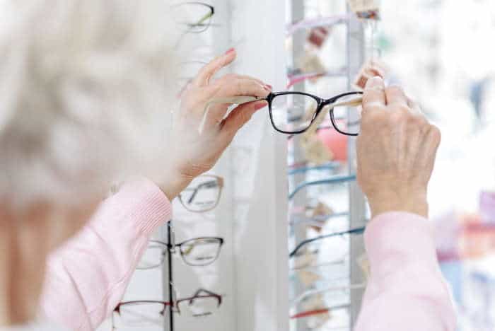 older woman picking a pair of reading glasses