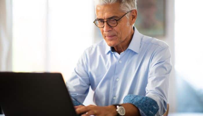 man wearing glasses working at laptop