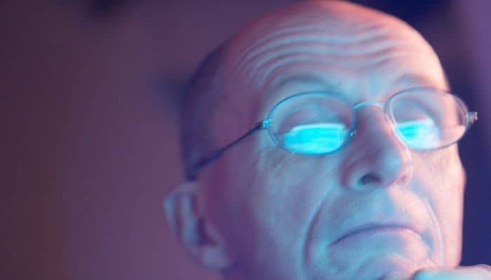 man with computer screen reflecting off eyeglasses