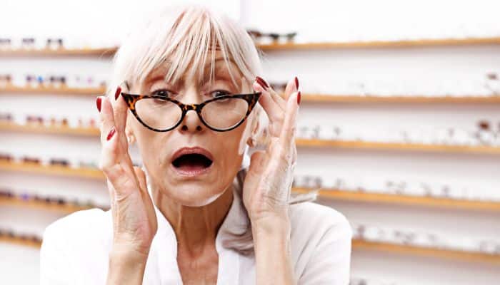 older woman trying on cat eyeglasses in optical shop