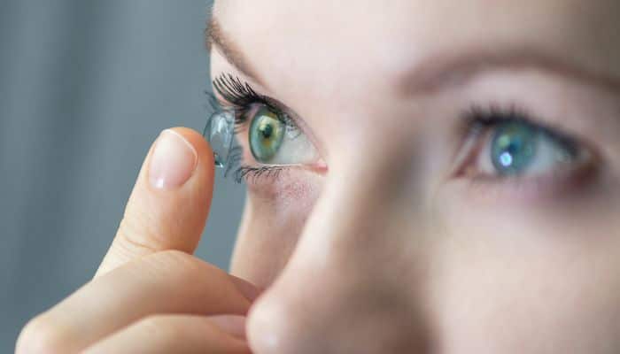 closeup of woman putting contact lens in eye