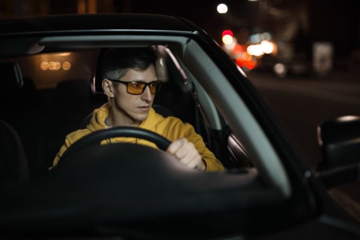 man wearing yellow lens glasses while driving at night