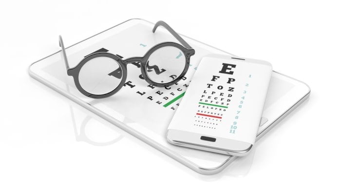 eyeglasses on top of tablet and smartphone with eye test