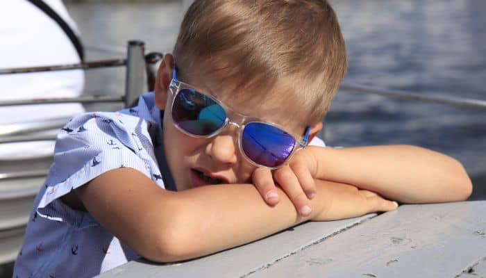 young boy wearing sunglasses leaning on picnic table
