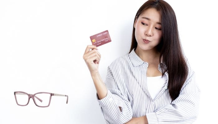 woman holding credit card eyeing a pair of glasses