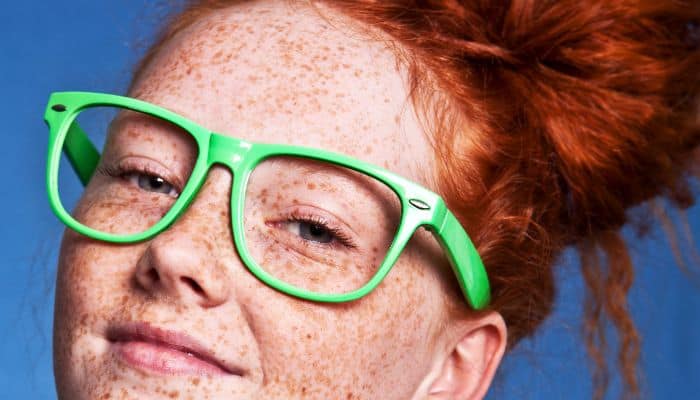 freckled redhead with neon green glasses