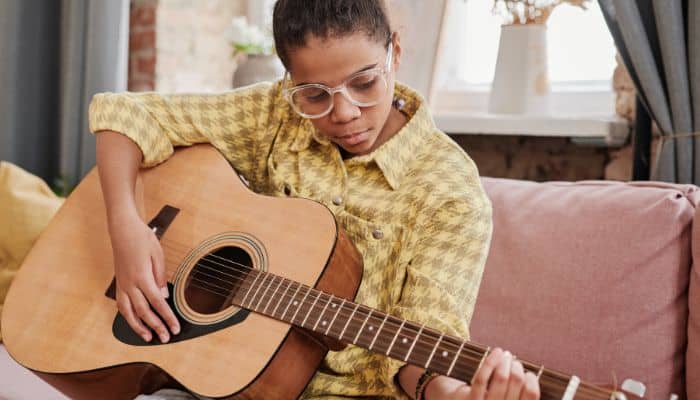 girl playing guitar in clear frame glasses