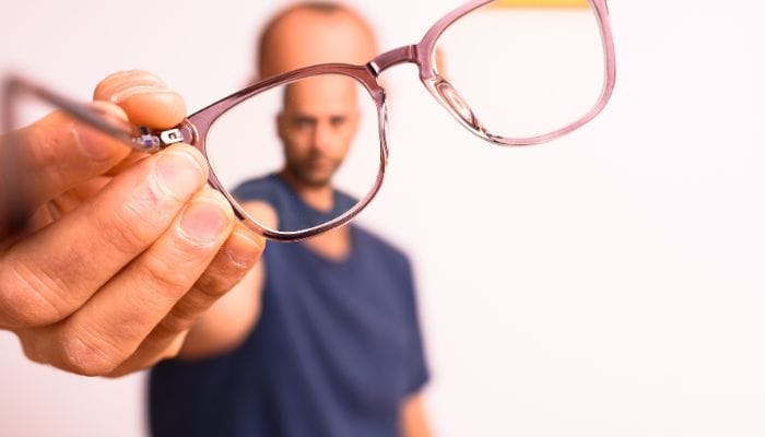man holding a pair of glasses towards the viewer